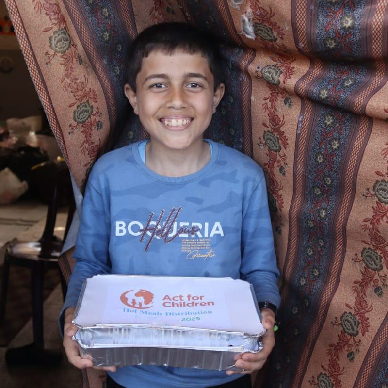 En pojke i Gaza tar emot ett varmt mål mat från Act for Children