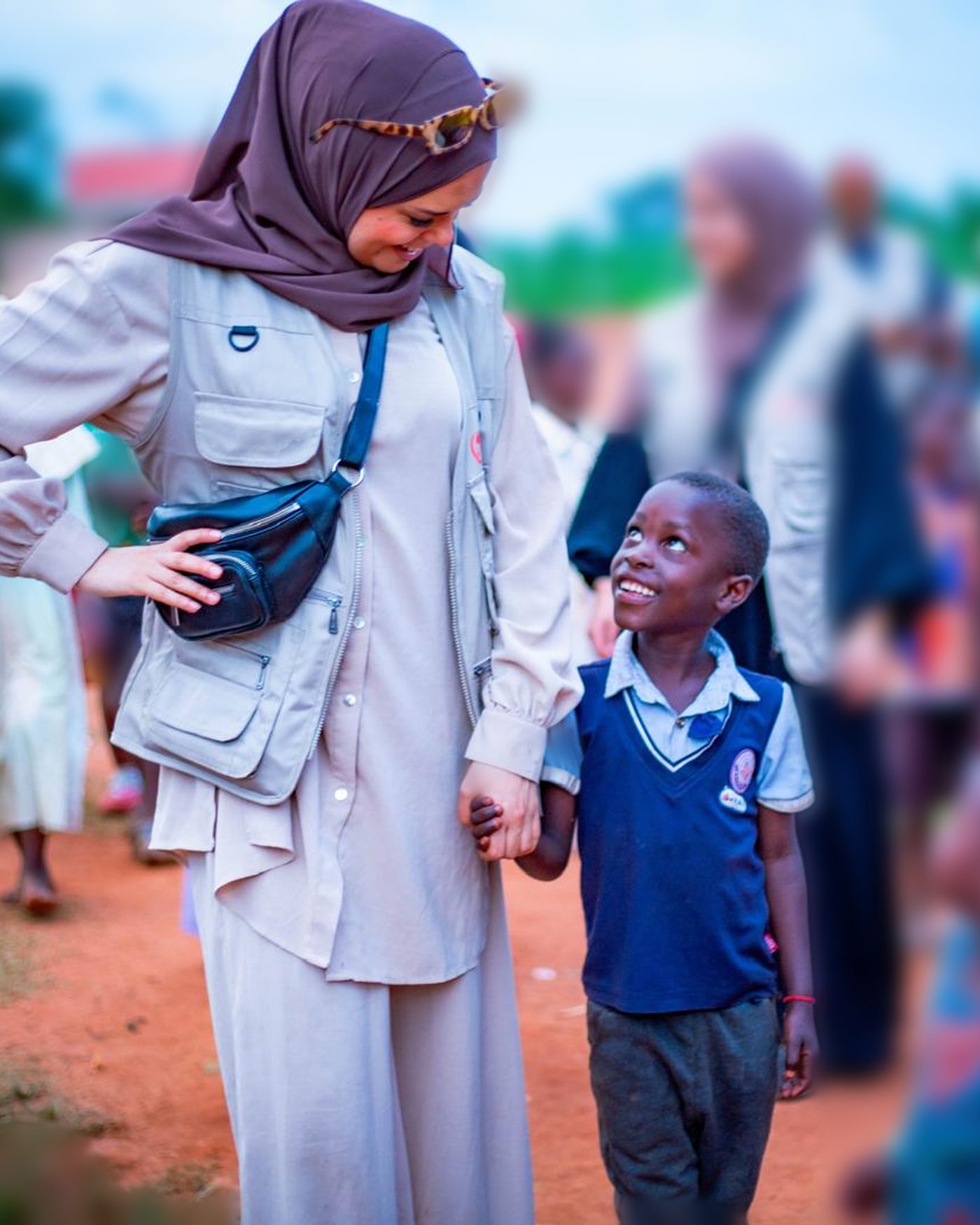 En volontär från Act for Children håller ett barn i handen i en by i Uganda